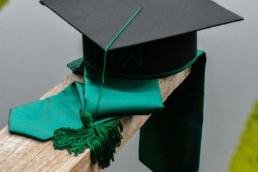 a graduation cap and a green tassel on a piece of wood